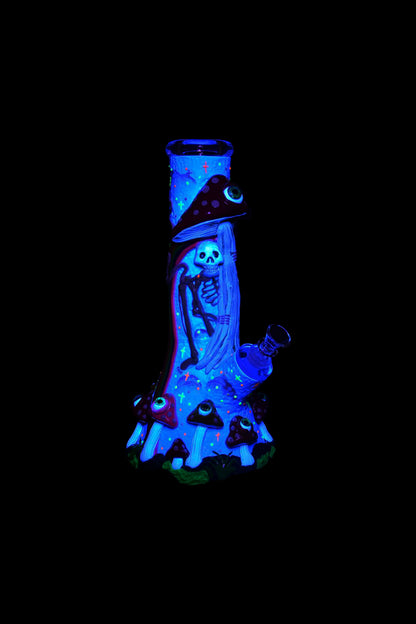 Glow-in-the-dark glass water pipe shaped like a skeleton wearing a witch hat, surrounded by glowing mushrooms.