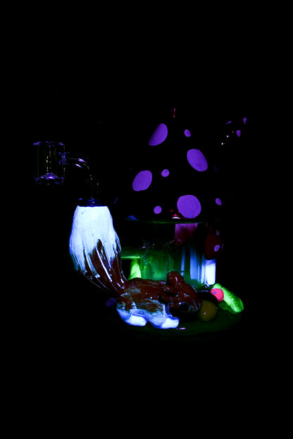 Psychedelic glass sculpture resembling mushrooms and alien flora, illuminated with vibrant purple and green lights, likely a display piece for a cannabis shop.