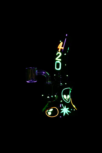 A glowing, neon-lit cannabis oil rig with “420” vertically stacked above it, surrounded by stylized alien eyes and floral accents on a black background.