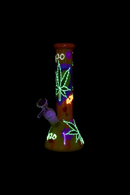 A glowing glass water pipe decorated with cannabis leaves and “420” text, alongside a metal dab tool.