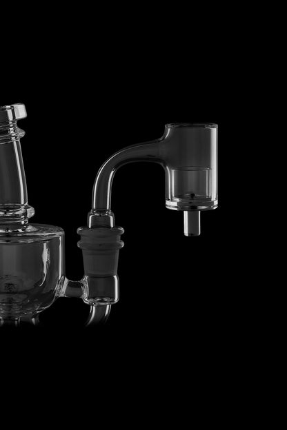 Clear glass dab rig with accessories against a black background.