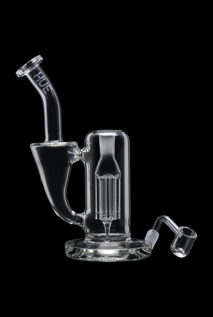 Clear glass dab rig with accompanying nail and carb cap, isolated on black.