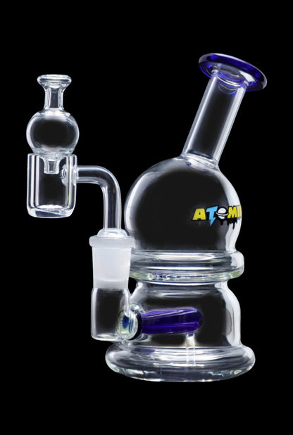 Clear glass bubbler with blue accents and a quartz dab rig attachment, branded "ATOMIC."