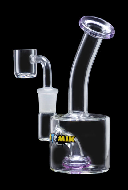 The Atomik Little Dipper Dab Rig appears in a studio shot, highlighting its clear glass construction and compact 5.25-inch size.