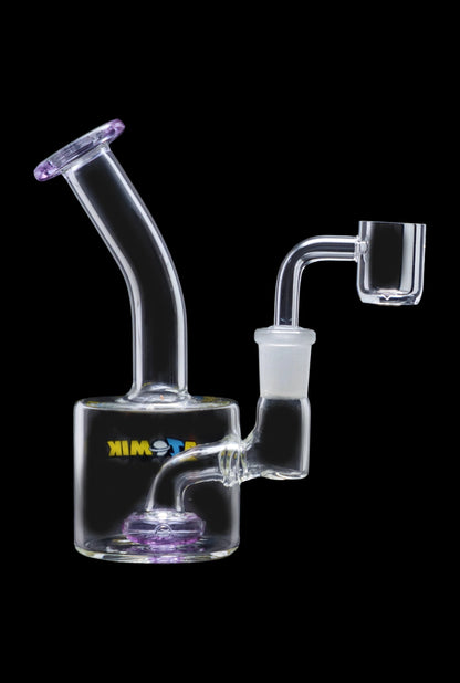 The Atomik Little Dipper Dab Rig is shown in a side view, highlighting its clear glass construction and compact size.
