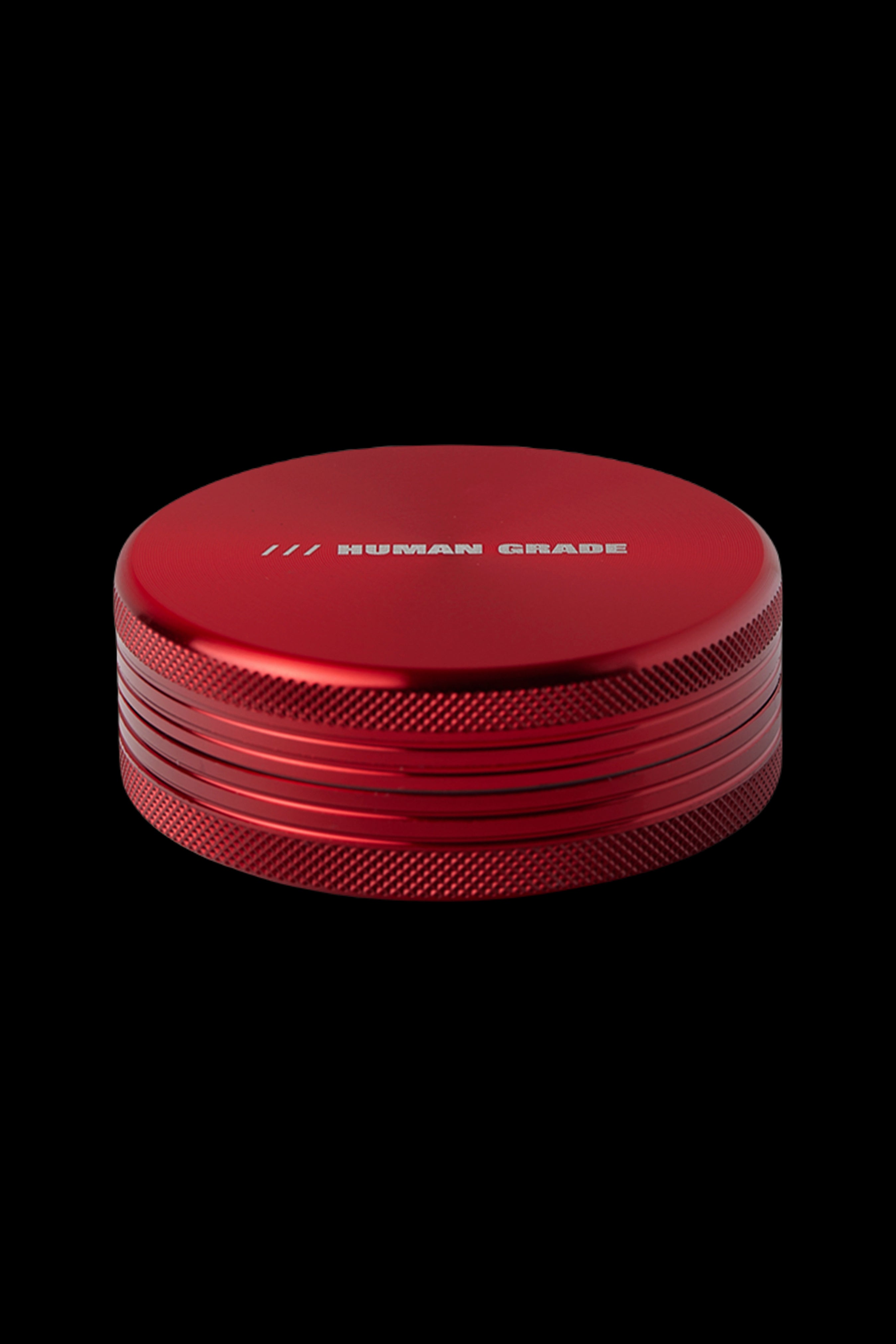 Red four-piece cannabis grinder with “HUMAN GRADE” engraved on top.