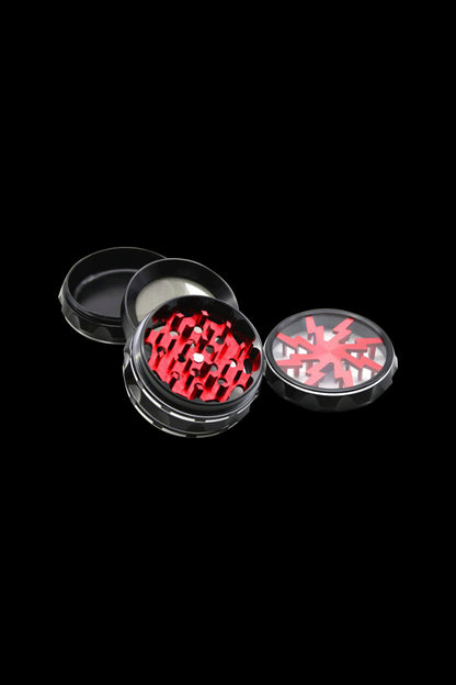 Black and red cannabis grinder with open compartments displaying grinding teeth.