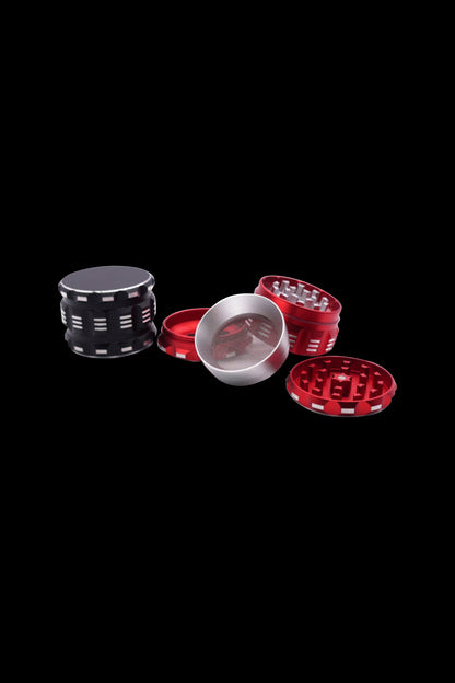 Red and black cannabis grinder disassembled on a black background.