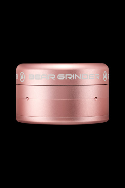 Rose gold cannabis grinder with branded text.
