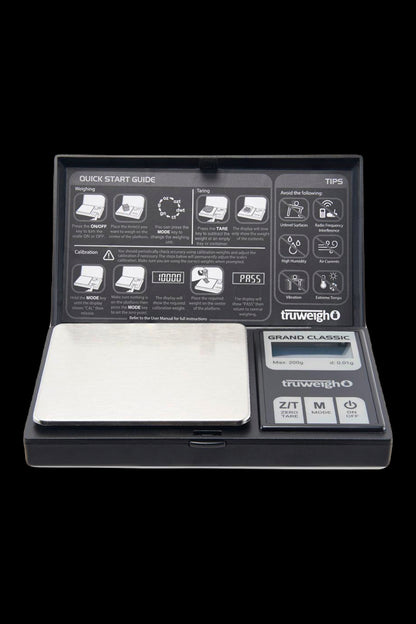 Top-down studio shot of the Truweigh Grand Classic Digital Scale - 200g x 0.01g showing the stainless steel weighing plate, open lid with quick-start guide, and control panel.