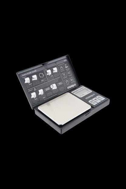 Angled close-up of the open Truweigh Grand Classic Digital Scale - 200g x 0.01g showing its stainless weighing platform, LCD panel and printed quick-start guide.