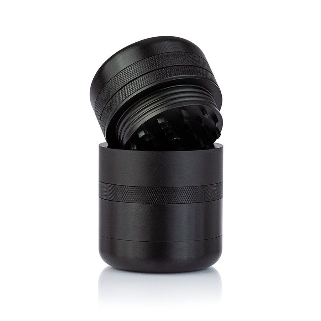 Angled close-up of the black RYOT GR8TR Solid Body Grinder with its top lid tilted to reveal textured knurling and interior teeth.