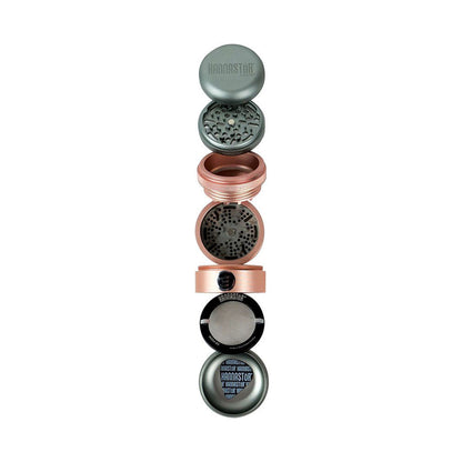 Vertical exploded view of the RYOT GR8TR Solid Body Grinder showing its stacked metal chambers, screens, and patterned grinding plates against a white background