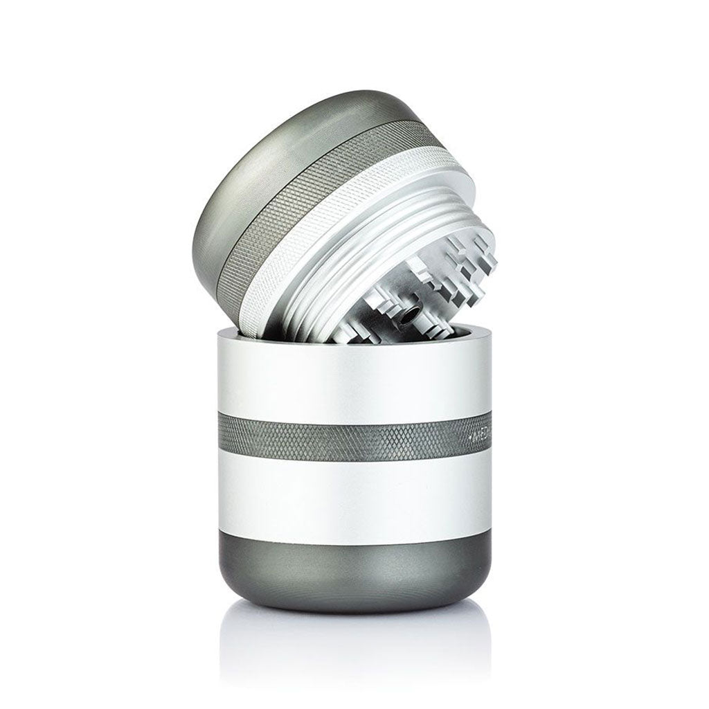 Angled close-up of the RYOT GR8TR Solid Body Grinder with its silver top lifted to reveal staggered metal teeth inside.