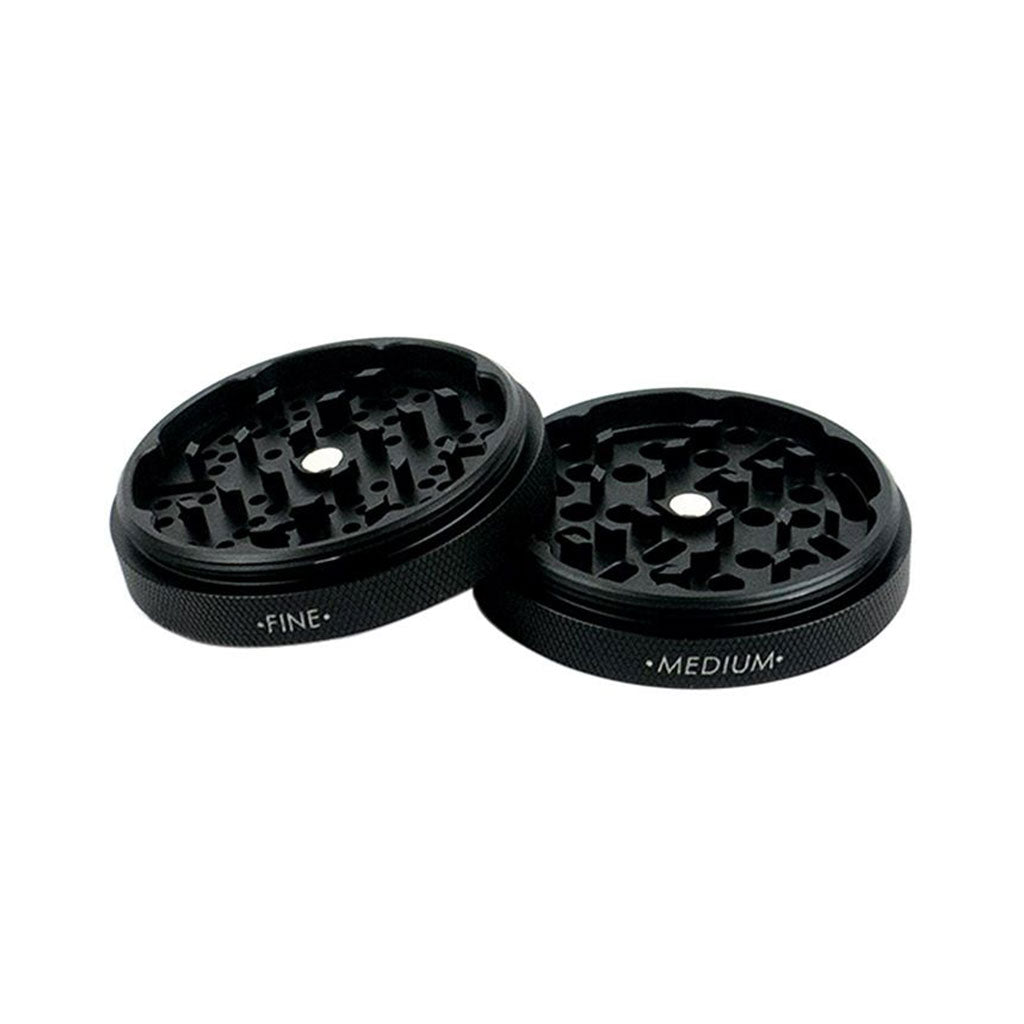 Angled top-down view of two black RYOT GR8TR Solid Body Grinder halves labeled "FINE" and "MEDIUM" against a white background