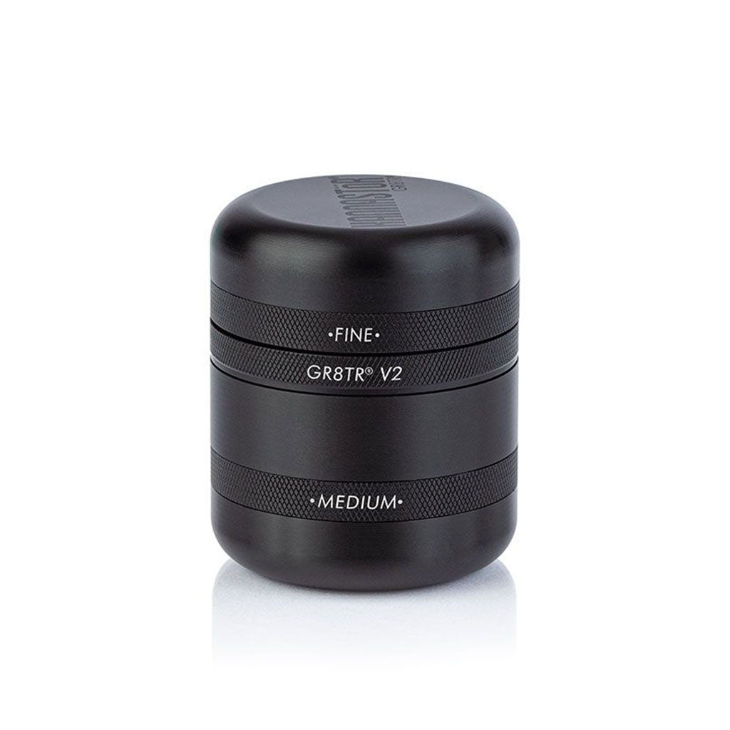 Centered front view of the black RYOT GR8TR Solid Body Grinder with stacked textured bands and white engraved labels on a white background