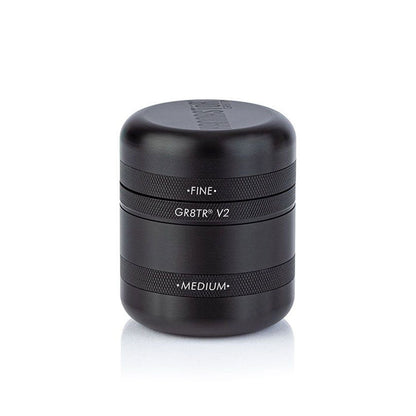 Centered front view of the black RYOT GR8TR Solid Body Grinder with stacked textured bands and white engraved labels on a white background