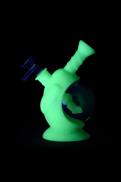 Glowing green glass bubbler with blue accents, isolated on black.