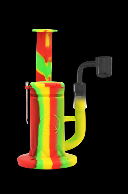 Red and green silicone dab rig with a quartz banger and dab tool against a black background.