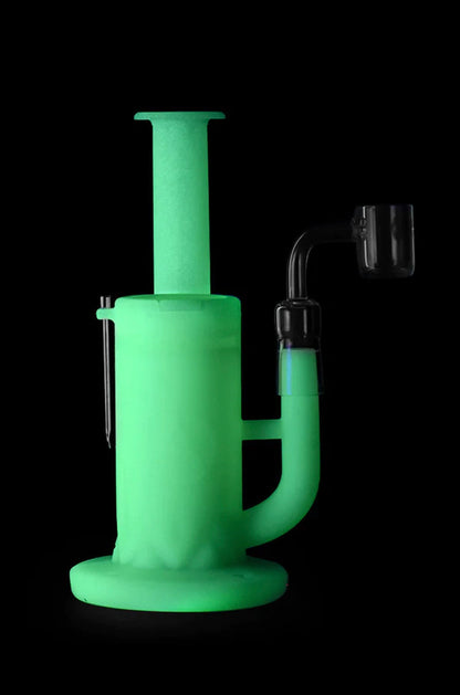 Green glass dab rig with accessories against a black background.