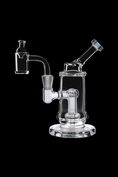 Clear glass dab rig with a quartz banger and carb cap, isolated on a black background.