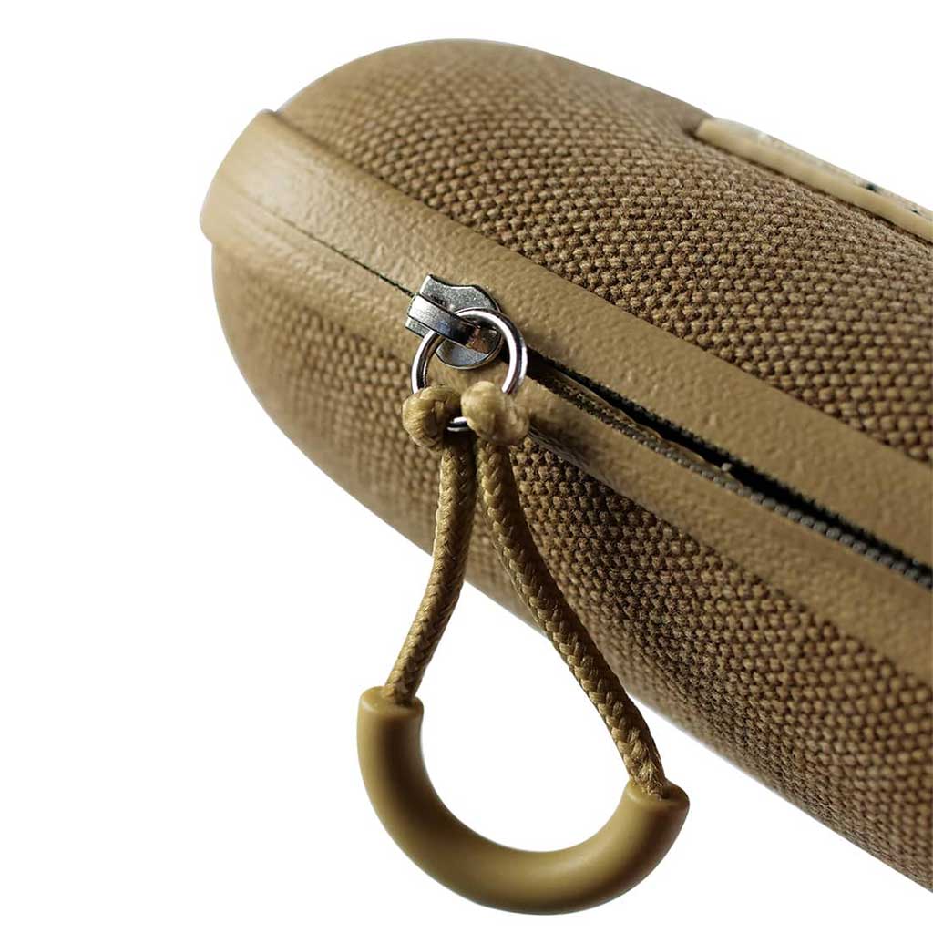 Close-up of the tan RYOT Hardcase zipper pull against textured fabric, shown at a slight angle on a white background