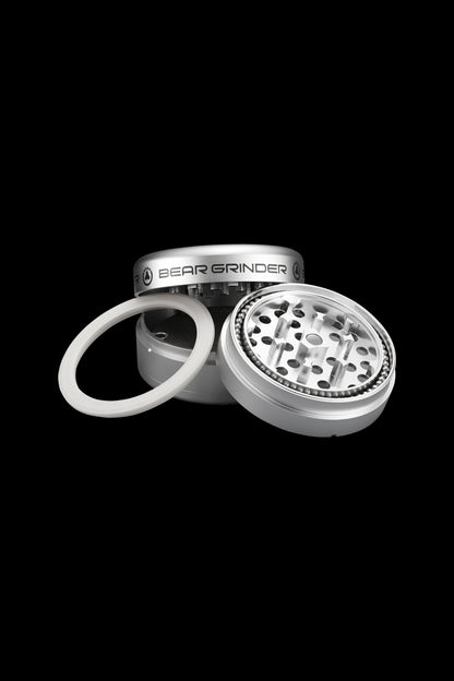 Silver four-piece cannabis grinder with open lid and spare O-ring.