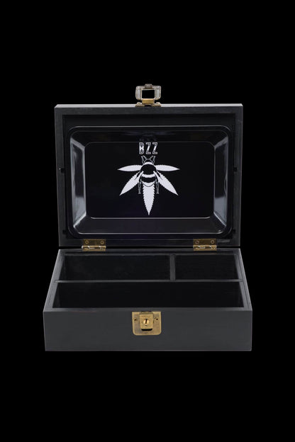 Black cannabis storage box with a leaf logo and internal compartments, open on a dark background.