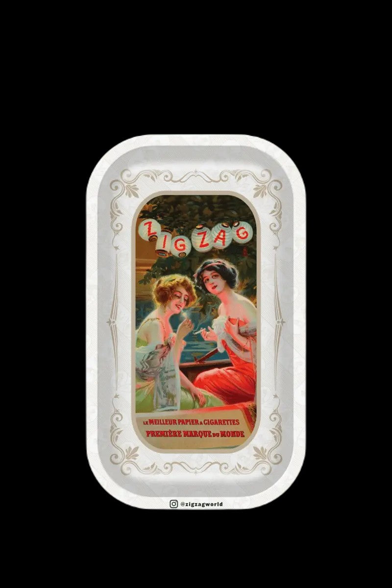 Vintage Zig-Zag rolling paper tin featuring an ornate design of two women in early 20th-century attire. <start_of_image>