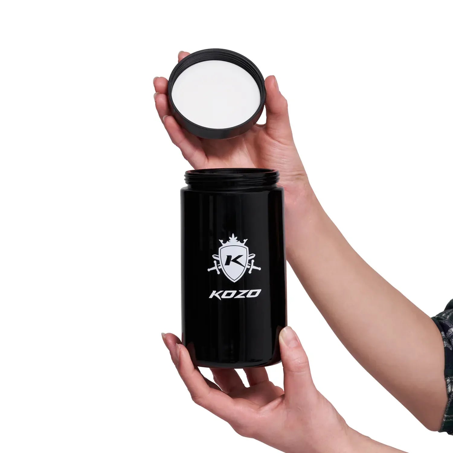 Hands holding the open Kozo Glass jars - 1 OZ in a centered front view, showing the black threaded lid lifted above the glossy black jar.