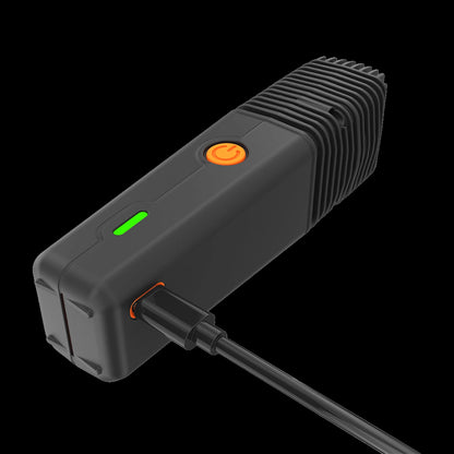Angled close-up of the Storz & Bickel Veazy Vaporizer showing its ribbed black heat-sink end, orange power button and green LED while plugged in