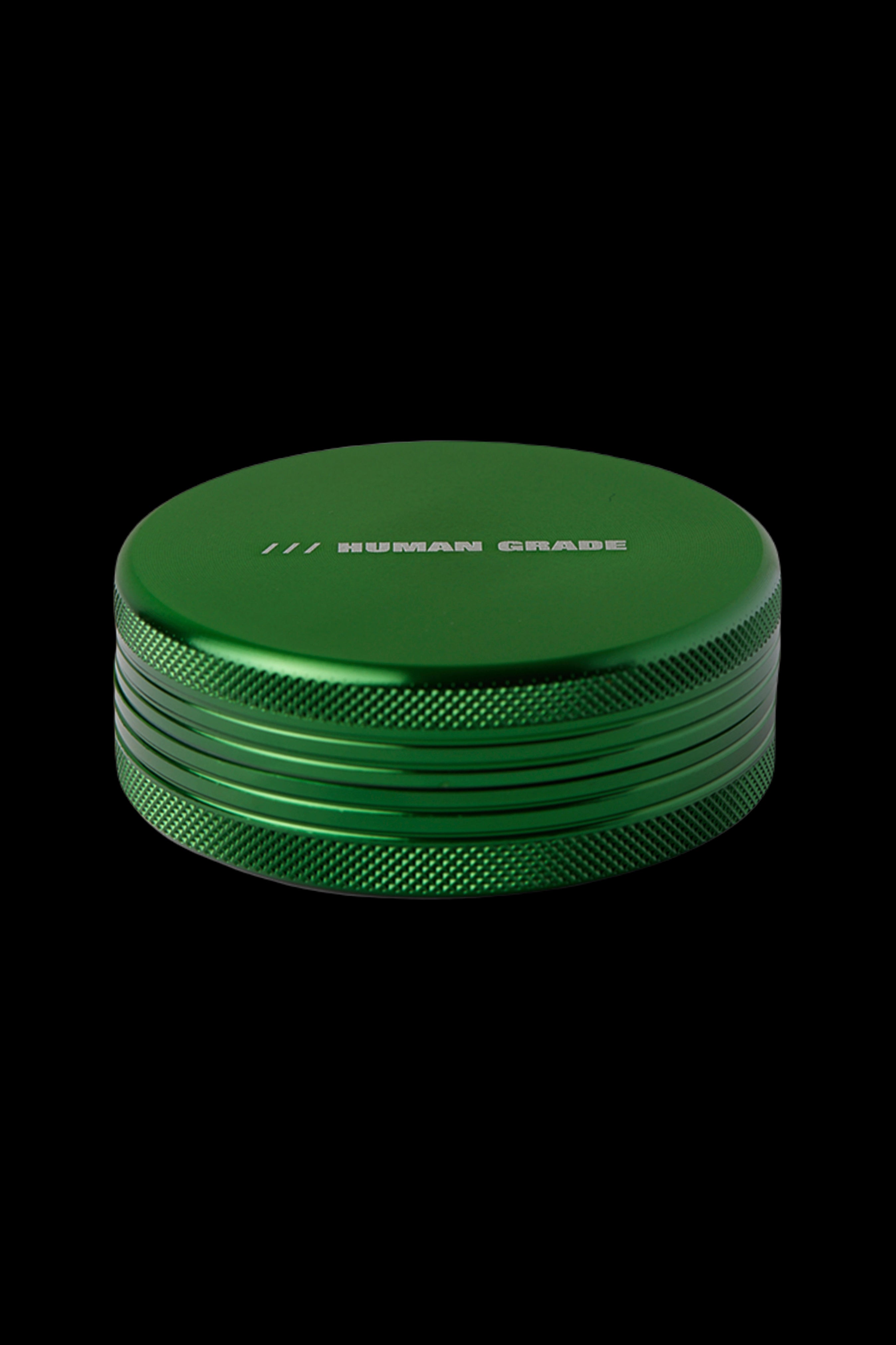 Green metal cannabis grinder with "HUMAN GRADE" text.