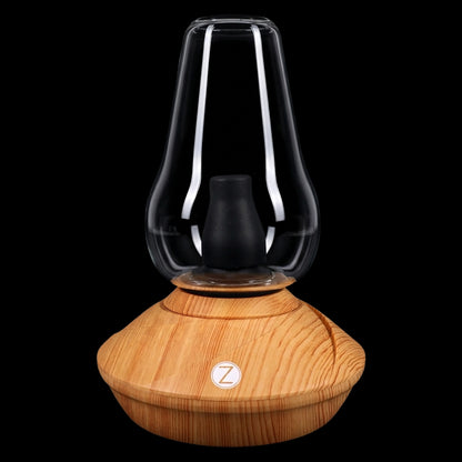 Front-facing close-up of the wood-colored Zenco Uno Desktop Vaporizer showing its glass bell chamber and black silicone insert atop a light wood grain base.