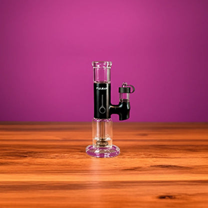 Center-framed Pulsar APX eRig on a wooden table against a magenta backdrop, shown in clear and black glass from the front.