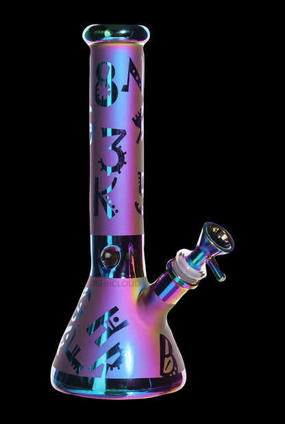 Angled front view of the Smoke Cartel Electro Plated Beaker Bong - 10 in. showing its iridescent purple-blue finish, black geometric decals, and attached bowl against a black background