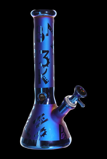 Front-facing view of the Smoke Cartel Electro Plated Beaker Bong - 10 in., showing a blue metallic finish with black geometric decals against a black background.