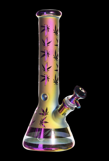 Angled front view of the Smoke Cartel Electro Plated Beaker Bong - 10 in., showing its iridescent purple-gold finish and black leaf motifs against a black background