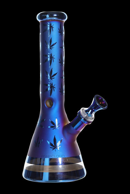Angled studio shot of the Smoke Cartel Electro Plated Beaker Bong - 10 in. in iridescent blue with black leaf silhouettes on a black background