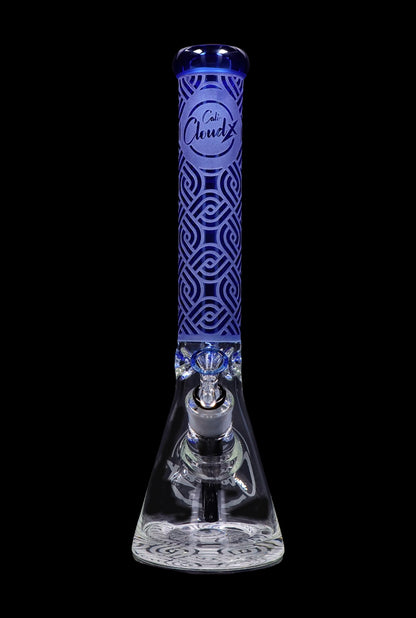 A front view of the Cloud Cali X 15-inch Engraved Thick Base Beaker Water Pipe, featuring detailed engravings on its clear glass base.