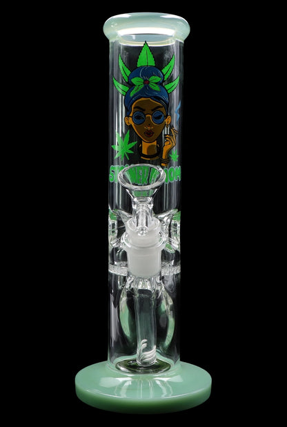 A vibrant green glass water pipe (bong) with a cartoon illustration of a woman wearing sunglasses and a headwrap, surrounded by cannabis leaves.