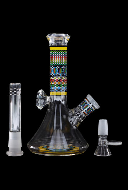Glass bubbler with patterned central section and accompanying glass pieces, isolated on a black background.