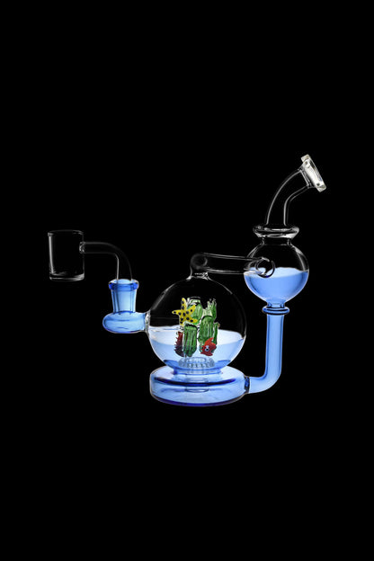 Blue glass water pipe with sculpted cannabis-themed artwork inside a spherical chamber.