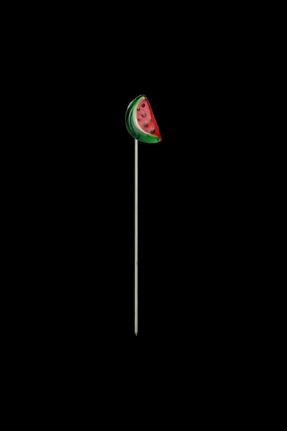 Watermelon-shaped dab tool with a long, thin metal tip on a black background.