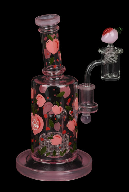 Angled close-up of the Pulsar Fruit Series Peaches & Cream Glow in The Dark Dab Rig Kit - 8" / 14mm F showing its pink glass body decorated with small peach motifs against a black background.