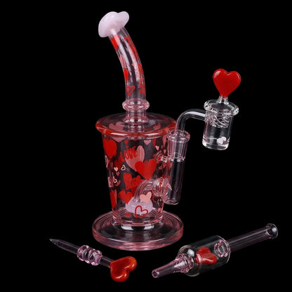 Angled close-up of the Pulsar Valentine's Love Hearts Glass Dab Rig Set - 8.5" / 14mm F showing pink glass with red heart motifs and a heart-topped banger against a black background