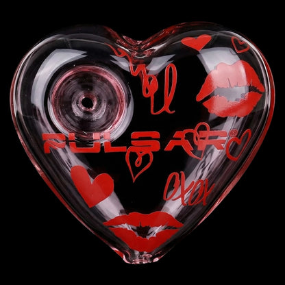 Close-up front view of the Pulsar Valentine's XOXO Glass Beaker Water Pipe & Hand Pipe Set - 10" / 14mm F, a heart-shaped clear glass piece decorated with red lips, hearts, and the Pulsar logo against a black background