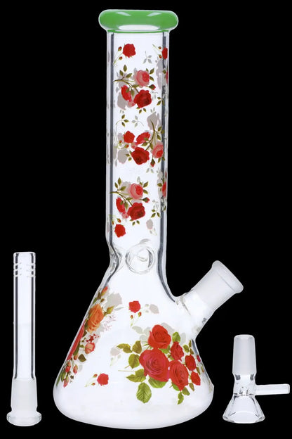 A glass bong decorated with red roses, alongside a glass downstem and bowl.