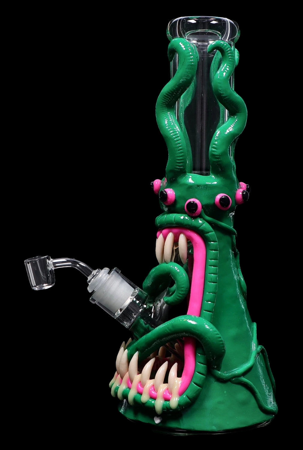 Green glass water pipe shaped like a monster with a pink tongue and exposed teeth, accompanied by a quartz banger.