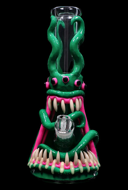 Green glass water pipe shaped like a monster with sharp, white teeth and pink accents, featuring a glass bowl.