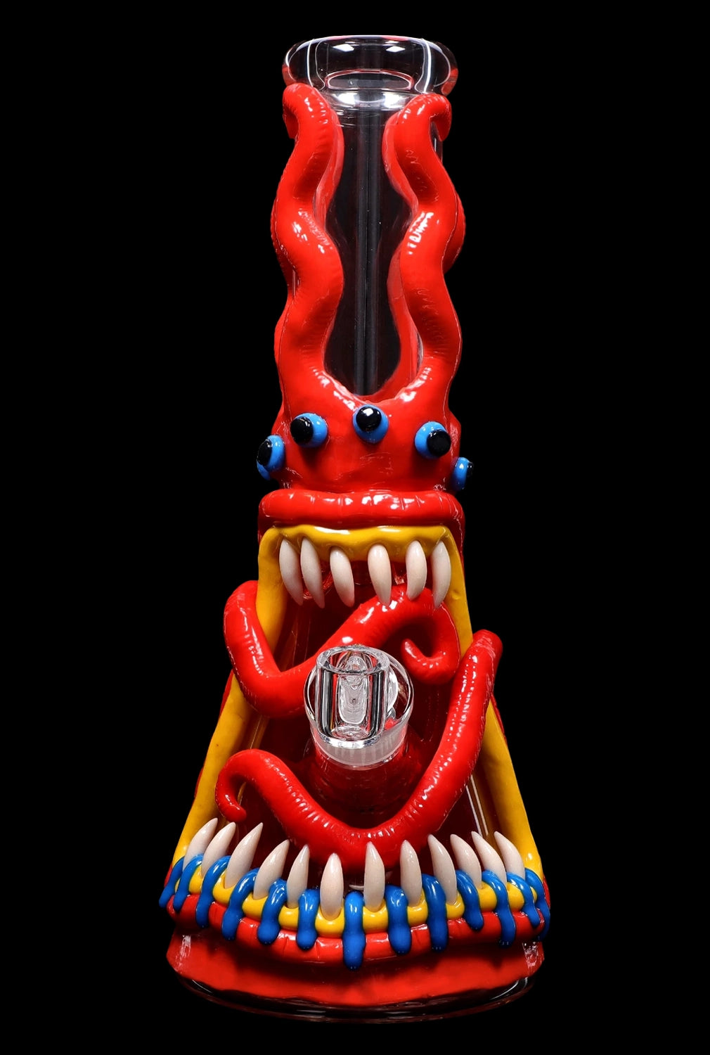 A vibrant red glass bong shaped like a monster with bulging blue eyes, sharp teeth, and colorful tentacles, set against a black background.